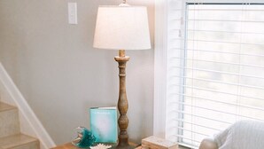 A room with a wooden table, a lamp, a book, and a window with blinds.