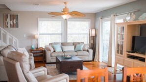 A living room with a sofa, armchair, coffee table, and a television.