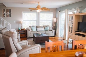 A living room with a sofa, armchair, coffee table, and a television.
