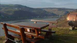 A wooden bench overlooking a river with a view of a town and hills in the distance. - Fantastic view high above the Rhine (Bacharach)