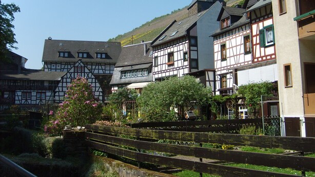 A traditional European village with half-timbered houses, a church with a pointed steeple, and a wooden bridge. - Fantastic view high above the Rhine (Bacharach)