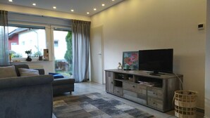 A modern living room with a grey sofa, a flat-screen TV on a wooden cabinet, and a patterned rug. - Fantastic view high above the Rhine (Bacharach)