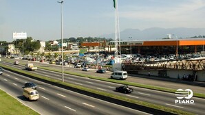 A highway with multiple lanes and vehicles, a large parking lot with ATADAO service station, and a flagpole with a flag. - Casa 1 (Rio de Janeiro)