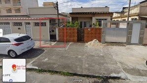 A residential area with a white car parked in front of a house with a gated entrance. - Casa 1 (Rio de Janeiro)