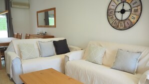 Una sala de estar con un sofá blanco, una mesa de centro de madera y un reloj de pared grande.