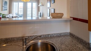 Een moderne keuken met een granieten aanrecht, een roestvrijstalen spoelbak en een hangende hanglamp.