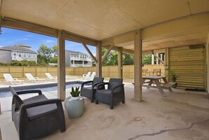An outdoor patio with a pool, lounge chairs, and a table.