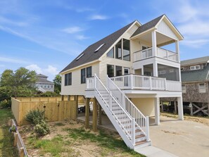 A two-story house with a balcony, a staircase, and a wooden deck.