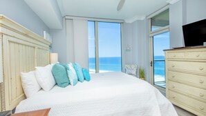 A bedroom with a large bed, a dresser, and a TV. - 2B Gulf Front*Tower 5*Stunning Views (Pensacola Beach)