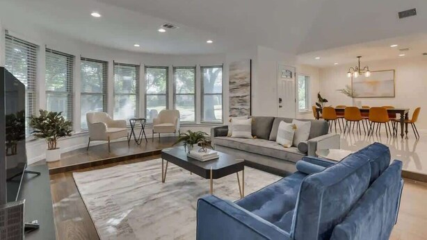 Una sala de estar moderna con un sofá azul, una mesa de centro y un comedor con una mesa y sillas.
