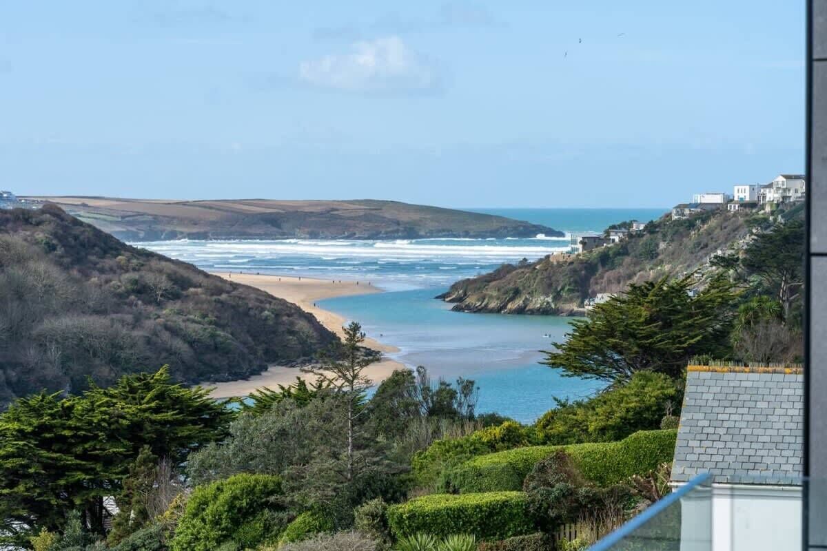 A coastal landscape with a beach, hills, and a view of the sea.