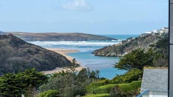 A coastal landscape with a beach, hills, and a view of the sea.