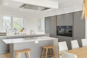Une cuisine moderne dotée d’un îlot central, de tabourets de bar et d’une table à manger.