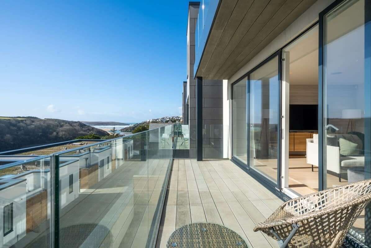 A modern balcony with glass railings overlooking a coastal landscape.