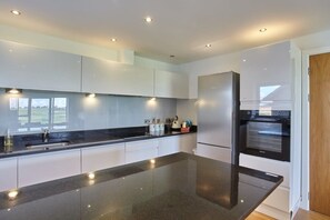 A modern kitchen with white cabinets, a black countertop, and built-in appliances including a refrigerator and oven.