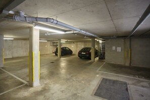 Un aparcamiento de varios niveles con pilares de hormigón e iluminación fluorescente.