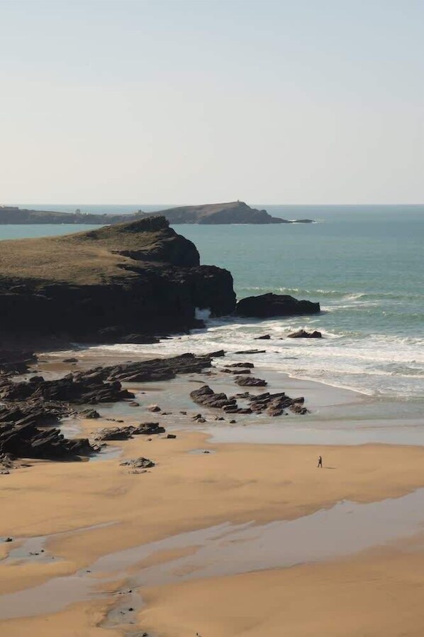 A coastal landscape with rocky formations and a sandy beach.