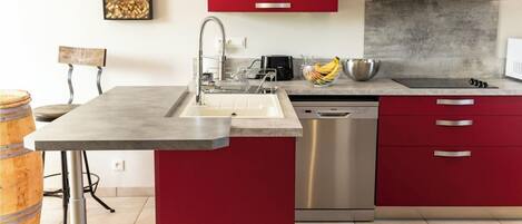 Una cocina moderna con un lavamanos de acero inoxidable, armarios rojos y un lavavajillas empotrado.