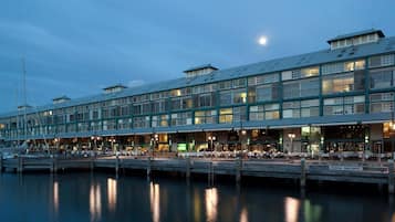 A waterfront building with multiple levels, large windows, and a dock extending into the water.