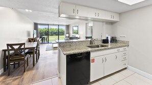 A modern kitchen with white cabinets, a granite countertop, and a dishwasher. - Cape Canaveral Charm Double Wide Patio & Heated Amenities (Cape Canaveral)