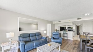A modern living room with a sofa, a coffee table, and a dining area with a table and chairs. - Cape Canaveral Charm Double Wide Patio & Heated Amenities (Cape Canaveral)