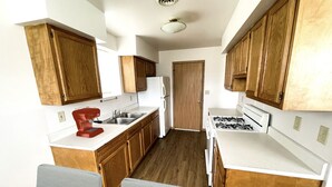 Una cocina compacta con armarios de madera, estufa a gas, refrigerador y lavaplatos.