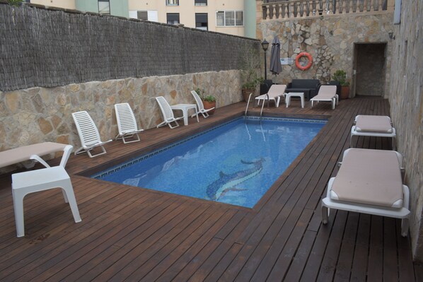 A pool area with lounge chairs and a stone wall. - Hotel Marbel Cala Ratjada (Capdepera)