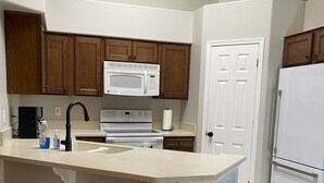 A kitchen with a central island, white appliances, wooden cabinets, and a trash bin. - SummerHaven 5 minute drive to river (Mohave Valley)