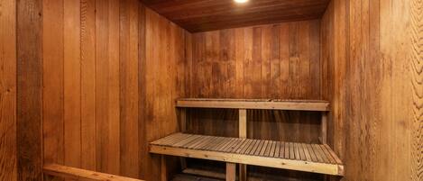 Una sauna de madera con bancos y un asiento tipo banca.