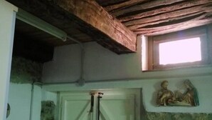Une pièce rustique avec des poutres apparentes, un mur en pierre et une porte blanche dotée d’une poignée en métal.