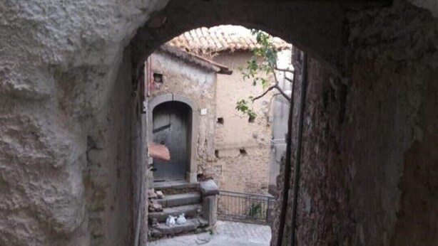 Un escalier étroit en pierre mène à un bâtiment dont le toit est recouvert de tuiles.