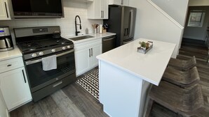 A modern kitchen with white cabinetry, stainless steel appliances, and a central island. - Beautiful 2BD + 2BA Home! King Beds! Hot Tub! Pool! Walk to downtown. (Whitefish)