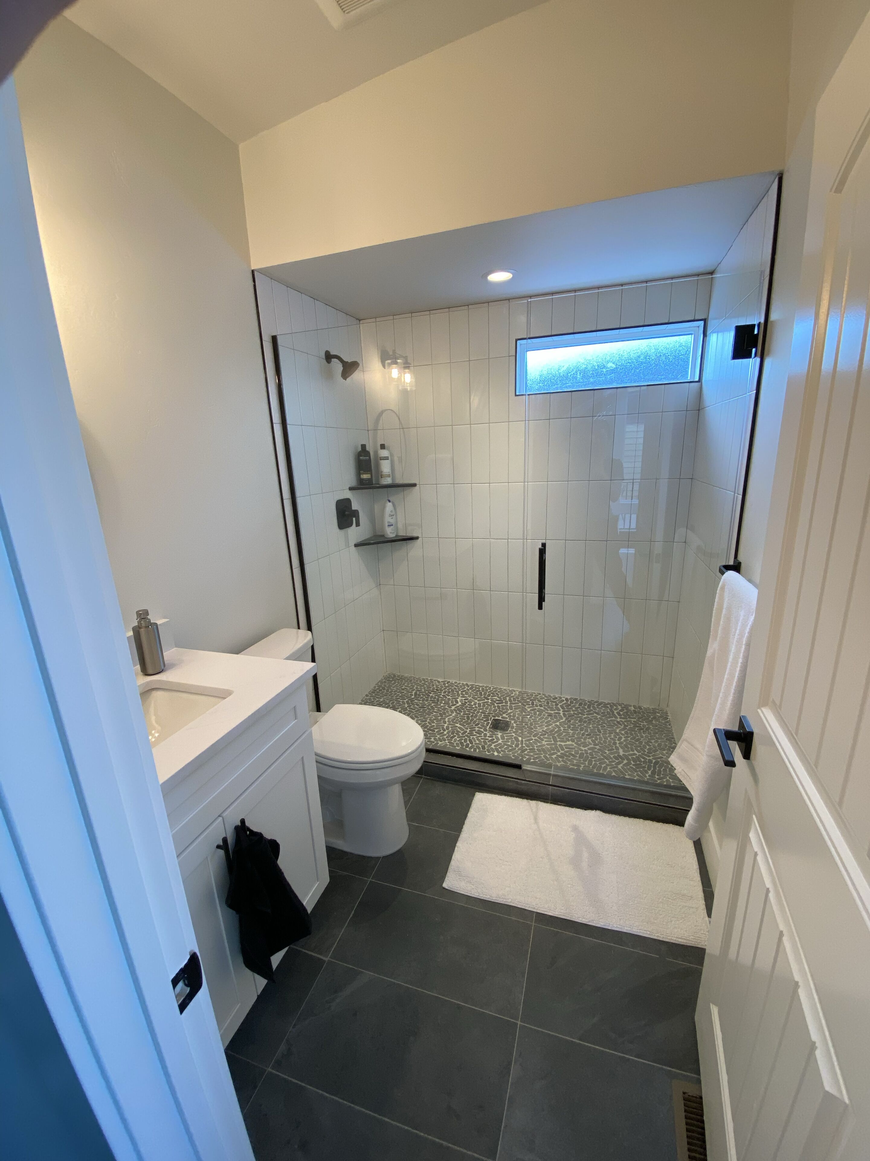 A modern bathroom with a shower, toilet, and sink.