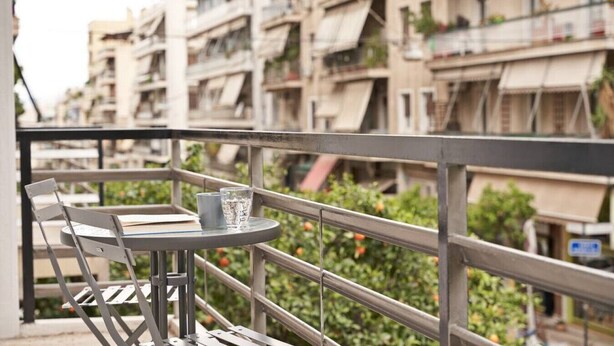 Un balcon avec une table et des chaises, donnant sur un quartier résidentiel composé de plusieurs immeubles.