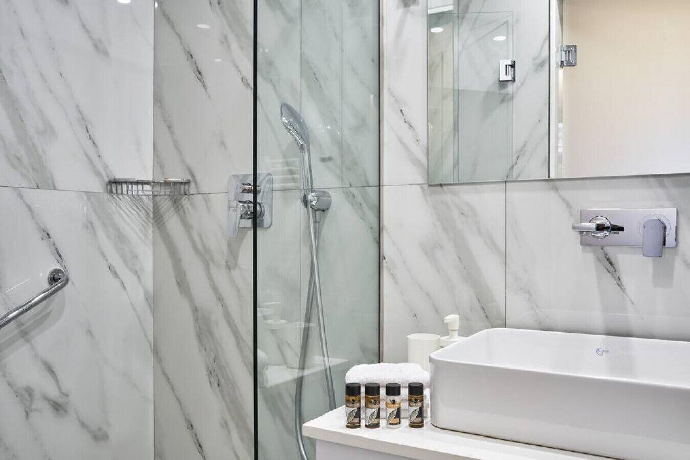 Une salle de bain moderne avec une douche à parois de verre, un lavabo blanc et un miroir au-dessus.