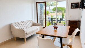 A modern living room with a sofa, a dining table with two chairs, and a balcony with outdoor furniture. - Apartment with terrace, swimming pool and private parking on the Costa Brava (Palafrugell)