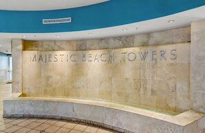 Un espace d’accueil avec un grand mur sur lequel est inscrit le texte : « MAJESTIC BEACH TOWERS ».