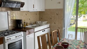 Una cocina con armarios blancos, una estufa, un fregadero y una mesa de comedor con sillas.