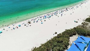 Una playa con una amplia zona de arena y un mar azul cristalino.