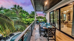A covered outdoor dining area with a pool, surrounded by lush greenery and a sunset view. - Walk to St. Armands and Lido Key Beach/Gulf Views (Sarasota)