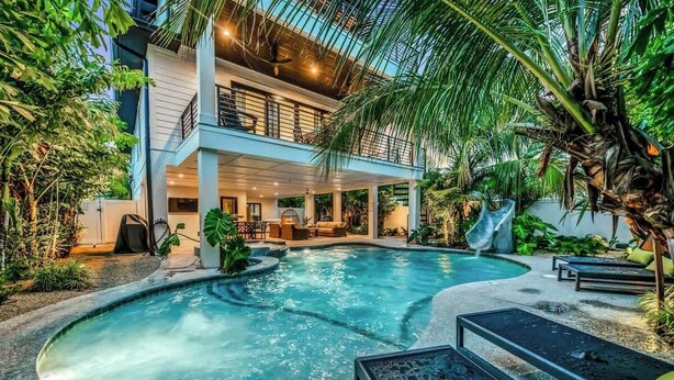 A modern building with a pool, outdoor seating, and lush greenery. - Walk to St. Armands and Lido Key Beach/Gulf Views (Sarasota)