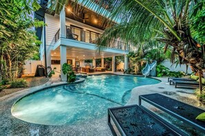 A modern building with a pool, outdoor seating, and lush greenery. - Walk to St. Armands and Lido Key Beach/Gulf Views (Sarasota)