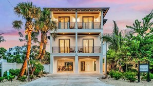 A two-story building with a balcony on the upper floor, surrounded by palm trees and greenery. - Walk to St. Armands and Lido Key Beach/Gulf Views (Sarasota)