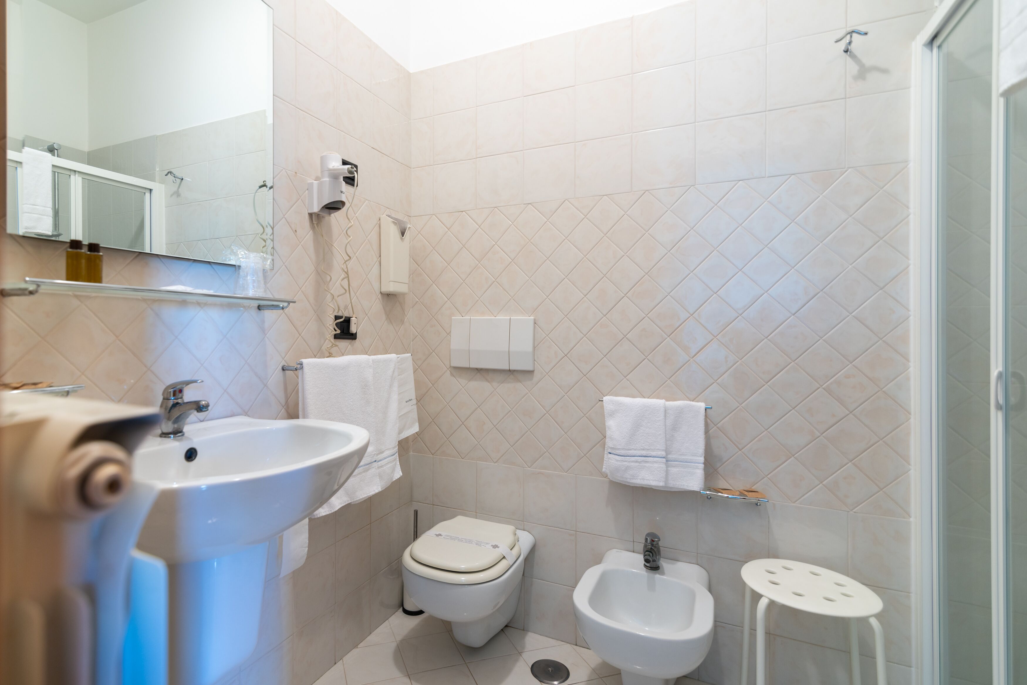A modern bathroom with a sink, toilet, bidet, and a glass shower enclosure.