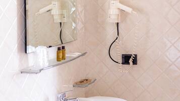 A bathroom with a white sink, a mirror, a hairdryer, and a small stool.