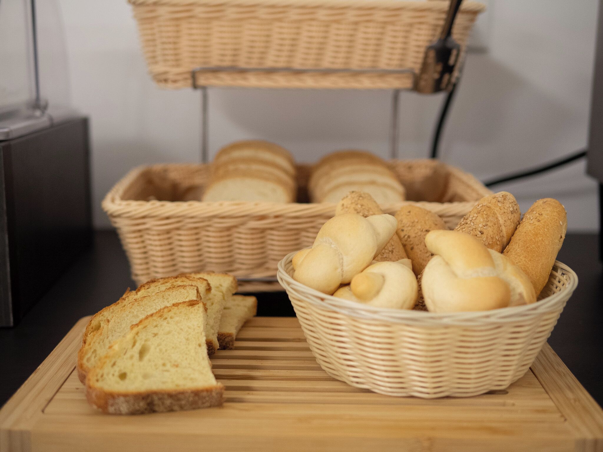 A basket of bread and a slice of bread on a cutting board.