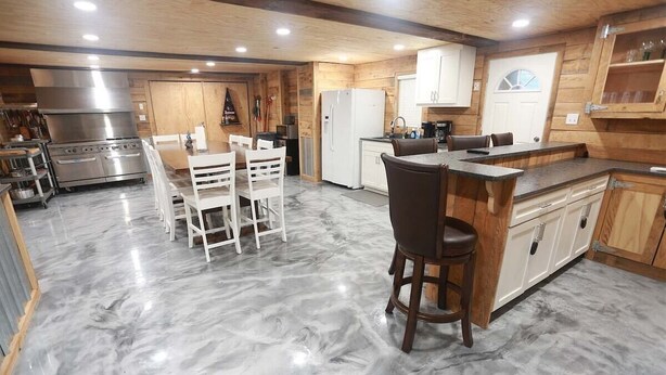 A kitchen with a marble floor, wooden cabinets, a stainless steel stove, and a bar area. - Flying Fish Yellow Fin-Beach Access-Island Realty (Grand Isle)
