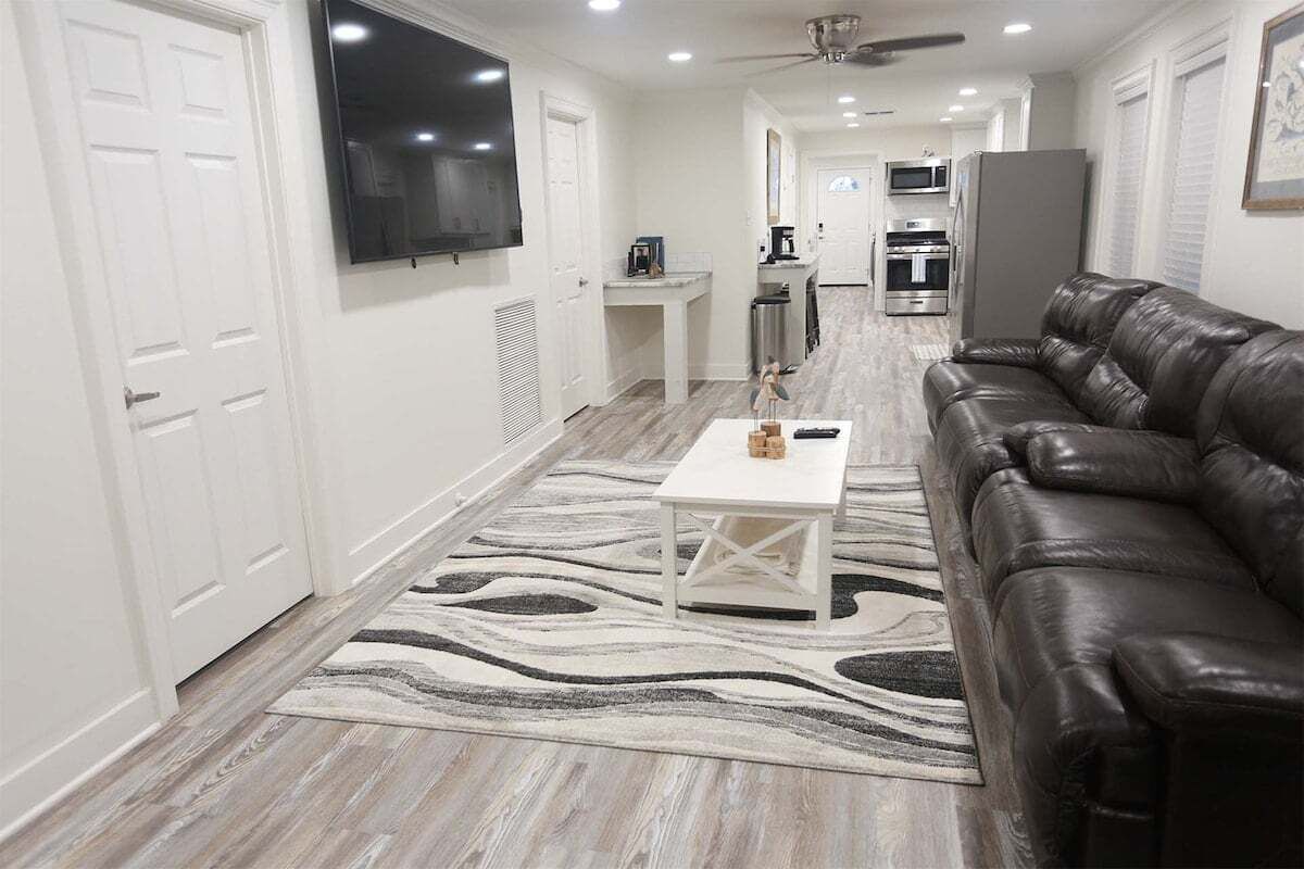 A modern living room with a leather sofa, a white coffee table, and a patterned rug.