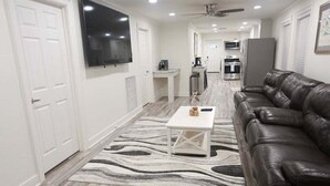 A modern living room with a leather sofa, a white coffee table, and a patterned rug. - Flying Fish Yellow Fin-Beach Access-Island Realty (Grand Isle)