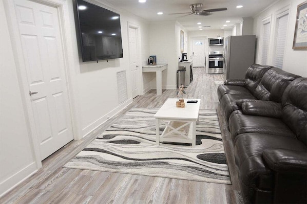 A modern living room with a leather sofa, a white coffee table, and a patterned rug.